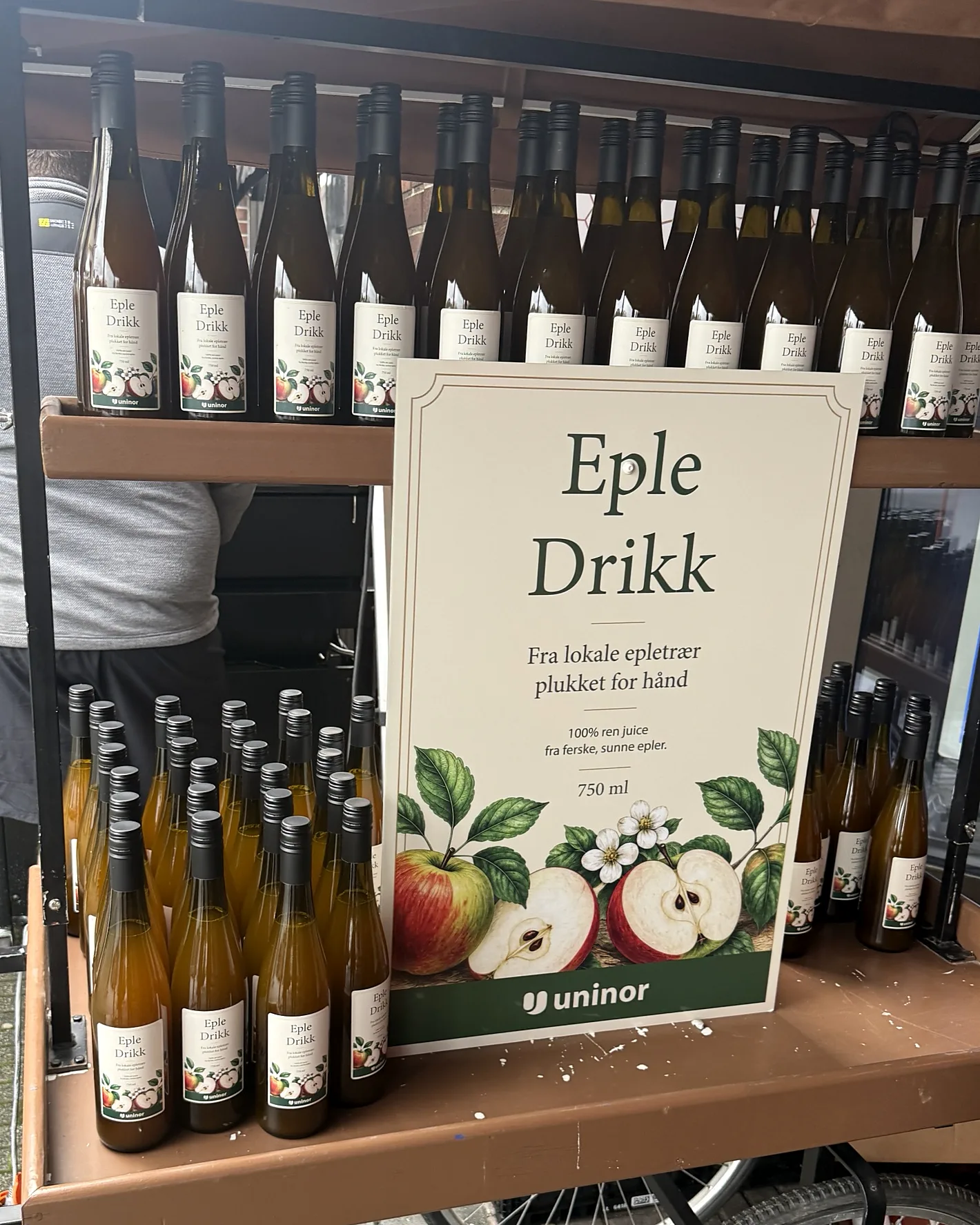 Uninors salgsvogn med Eple Drikk i store og små flasker og en plakat i samme design som etiketten